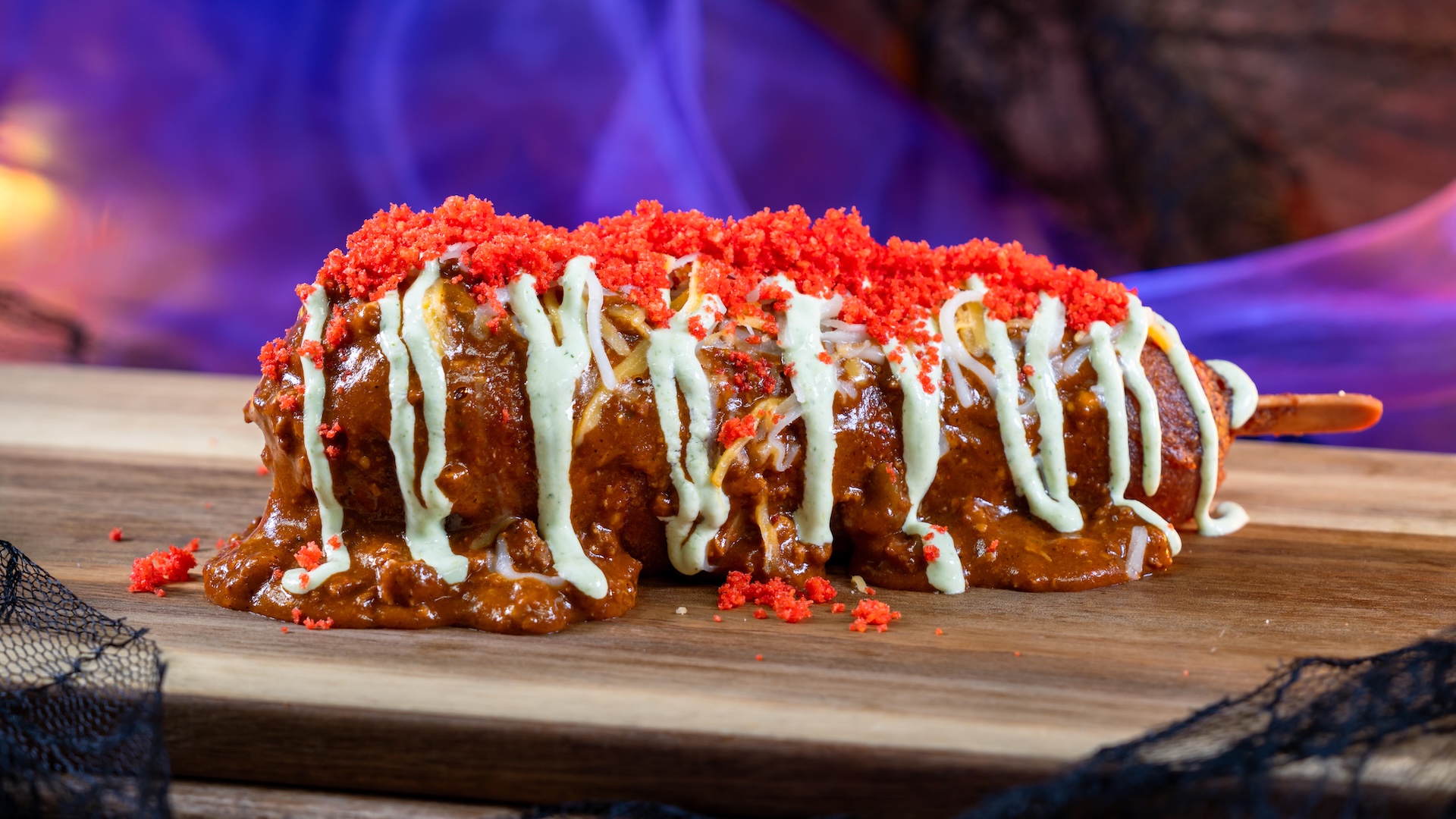 Spicy Chili-Cheese Corn Dog: Classic corn dog topped with spicy chili, jalapeño-cilantro crema, cheddar, and hot cheese puff dust served with choice of a Cuties Mandarin Oranges or potato chips (New)