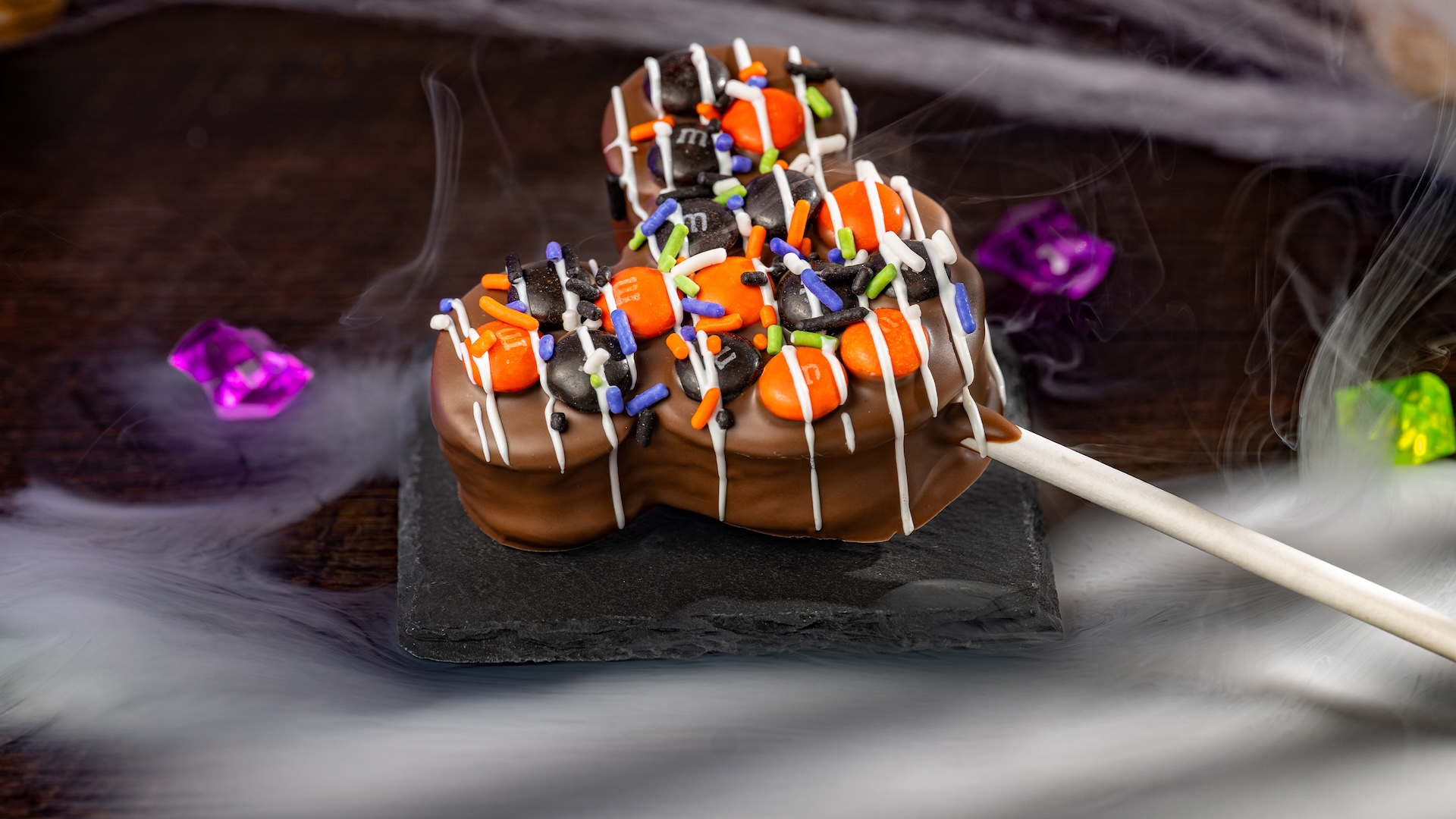 Mickey Halloween Marshmallow Pop with M&M’S Milk Chocolate Candies: Marshmallow with milk chocolatey coating, M&M'S milk chocolate candies Halloween blend, Halloween sprinkles, and white chocolatey drizzle 
