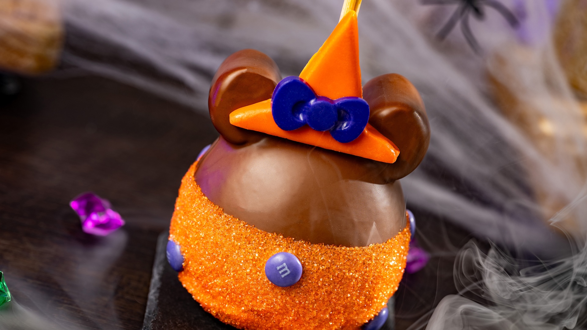 Minnie Witch Caramel Apple with M&M’S Milk Chocolate Candies: Granny Smith apple with marshmallow ears dipped in Werther’s Original caramel and milk chocolatey coating with M&M'S milk chocolate candies, orange sanding sugar, and a chocolatey witch hat 