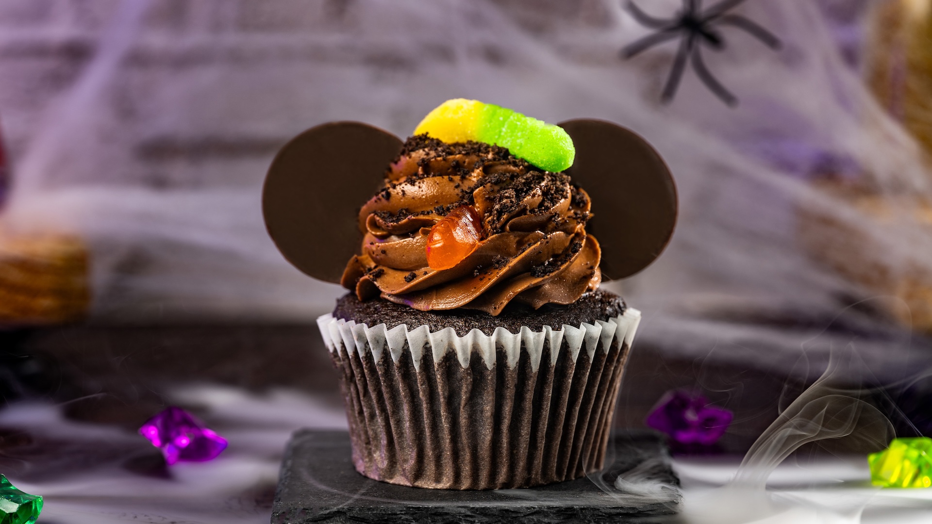 Mickey Halloween Chocolate Cupcake: Chocolate cupcake with chocolate buttercream frosting, dark chocolatey ears, crushed chocolate cookies, and a gummy worm (New) 
